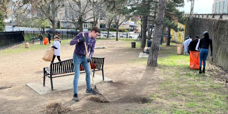 People rake and bag leaves in park for Earth Day cleanup