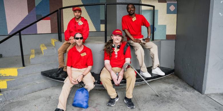 Four men sit on benches in front of stairs and railing