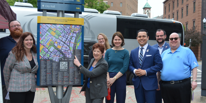 City and state officials standing outside wayfinding signage