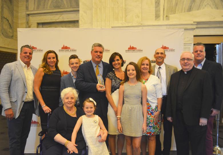 Award recipients stand in front of a step and repeat banner facing the camera and smiling