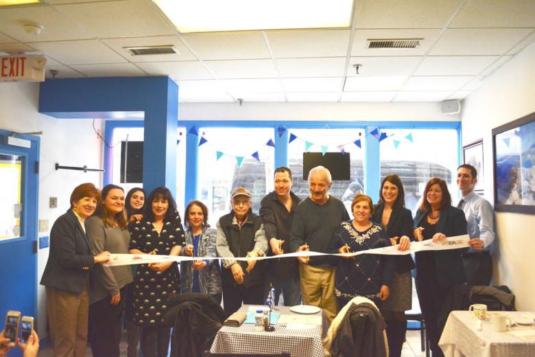 Employees stand with Albany Mayor and BID representatives holding a ribbon for their ribbon cutting ceremony