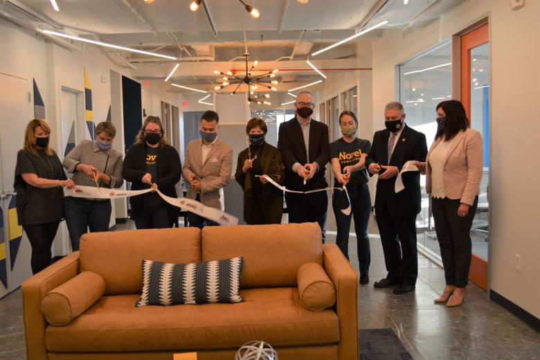 Employees stand with Albany Mayor and BID representatives holding a ribbon for their ribbon cutting ceremony