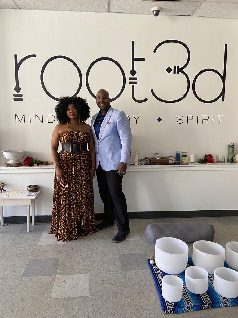 Two black business owners stand in front of their logo inside their business, Root3d