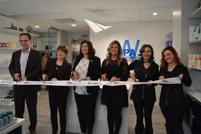 Employees stand with Albany Mayor and BID representatives holding a ribbon for their ribbon cutting ceremony