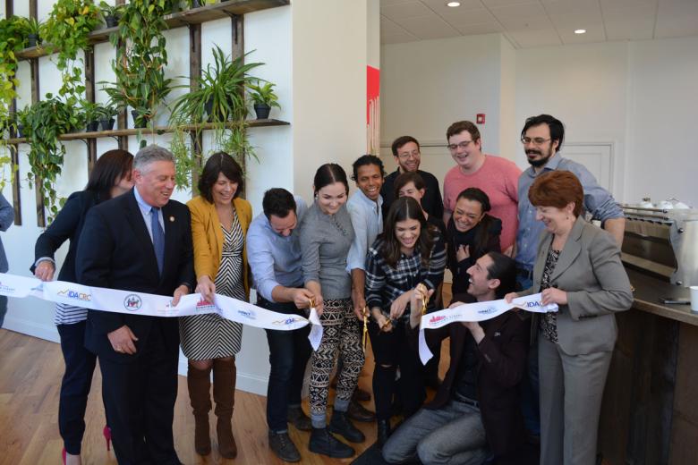 Ribbon cutting in front of a wall of greenery in the new cafe