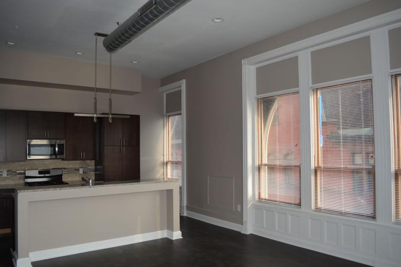 Interior view of a Steuben Place apartment, showing the high ceilings, windows, and kitchen space. 