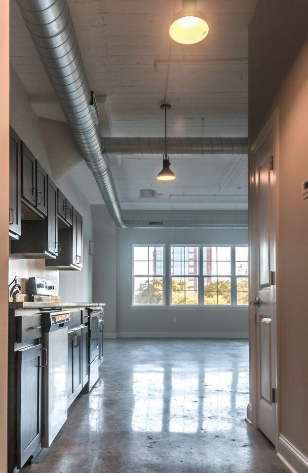 The Lofts apartment interior shot looking down a hallway at large windows and a wide open living space