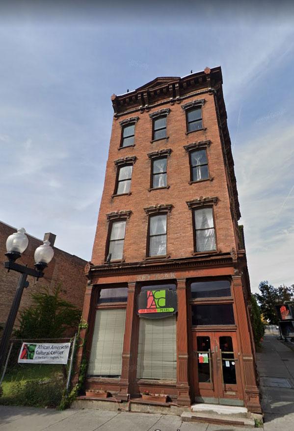 Exterior facade of a brownstone with the African American Cultural Center logo on the street level space