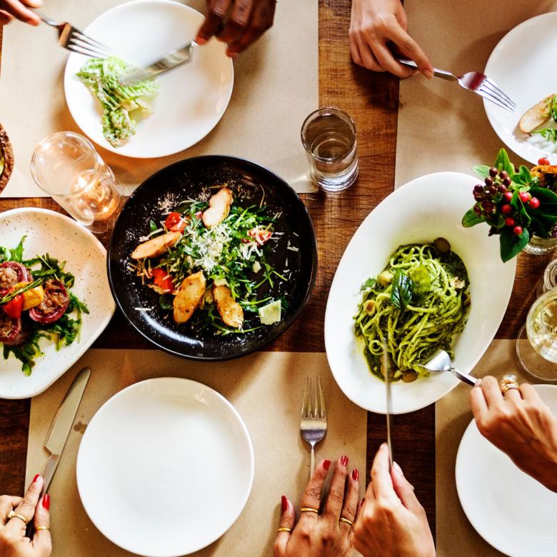 Overhead image of a group of dishes on a table, some plates are empty while some have meals like vegetable stir fry and pesto
