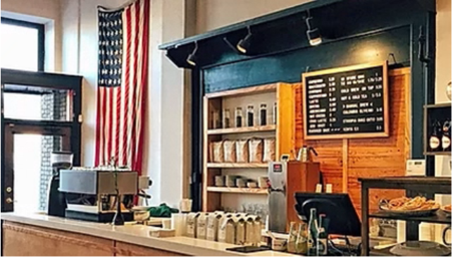 Interior of a business, looking at the counter with the register. A large american flag is hung from the wall near the front door.